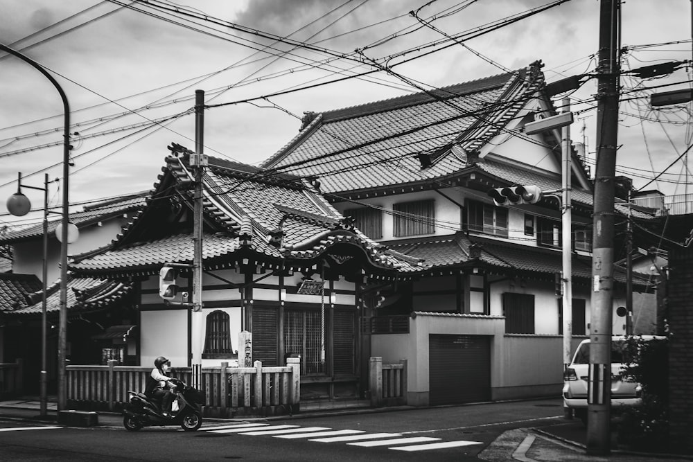 grayscale photo of 2 people sitting on bench in front of house