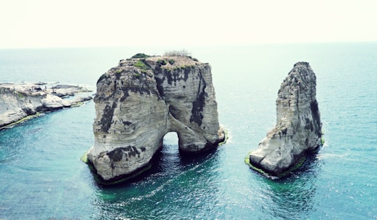 brown rock formation on sea during daytime in Raouche Rocks Lebanon