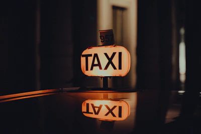 Close-up of a VIP taxi sign illuminated in blue on a sleek car at dusk.