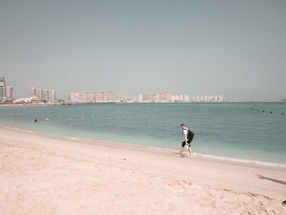 woman in black tank top and black shorts walking on beach during daytime