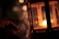 A smiling woman holding a glowing lantern in a cozy, softly lit room.