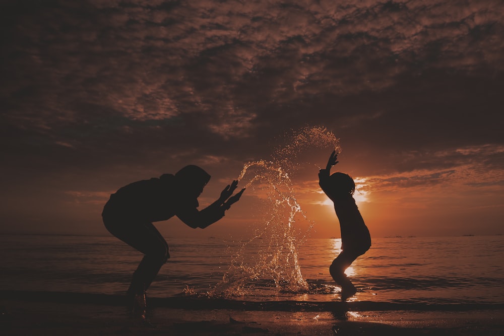 silhouette of man and woman kissing on beach during sunset