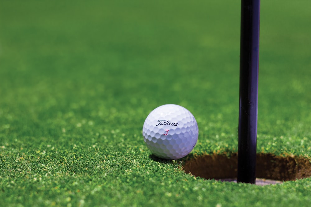 balle de golf blanche sur un terrain en herbe verte pendant la journée