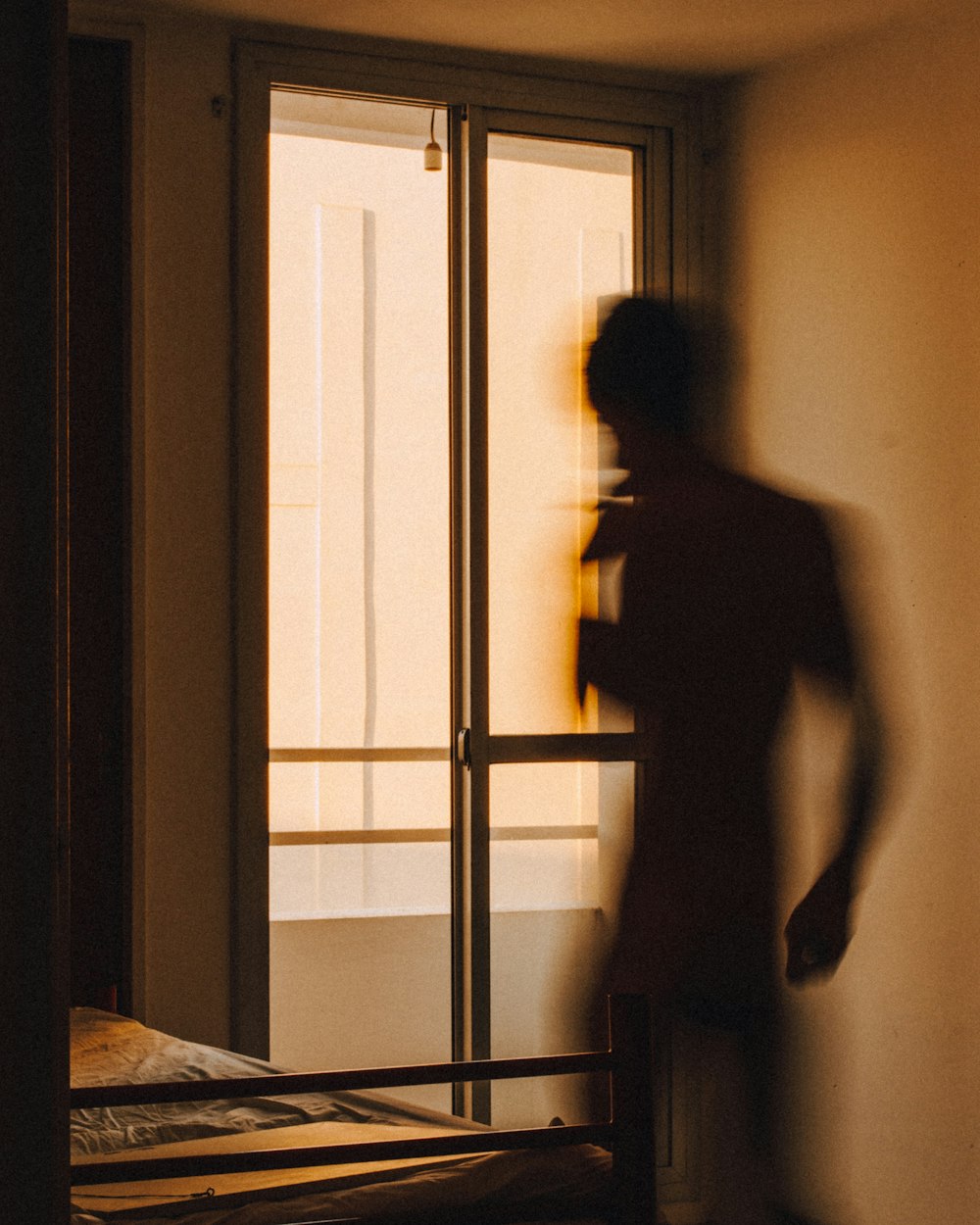 silhouette of man standing in front of window