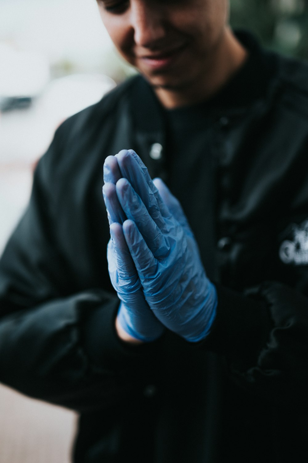 person in black jacket with blue gloves