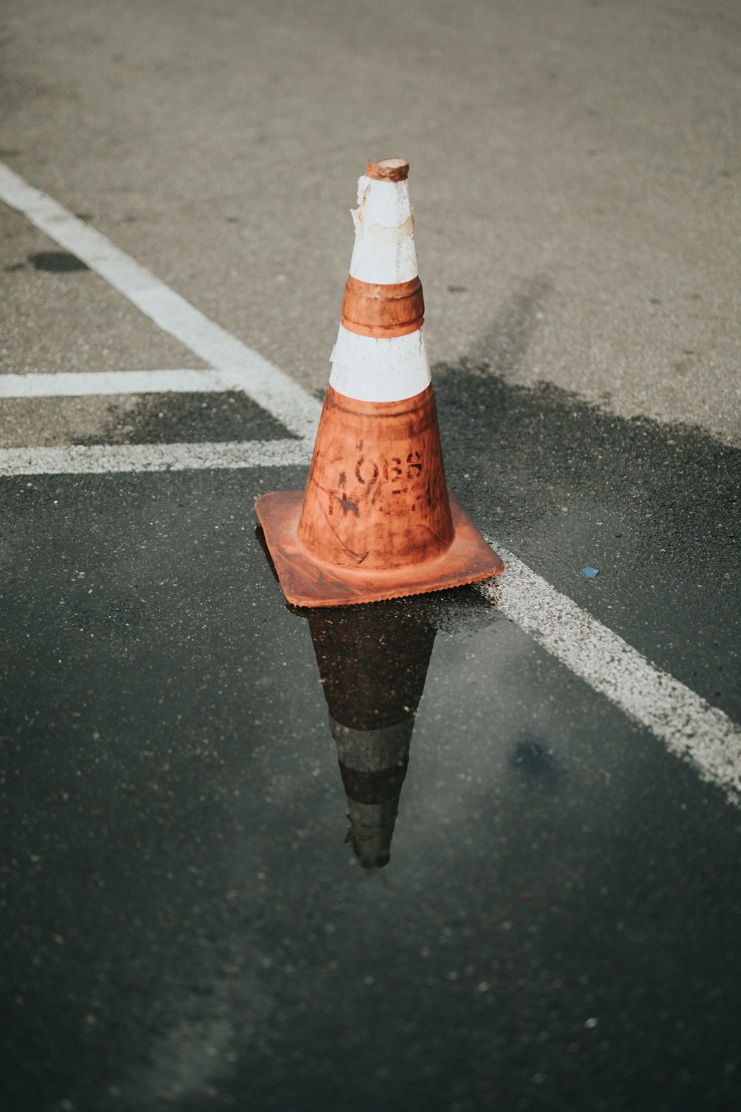 orange and white traffic cone on black asphalt road