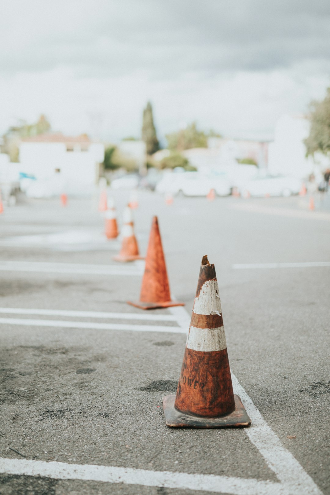 orange and white traffic cone on gray asphalt road during daytime