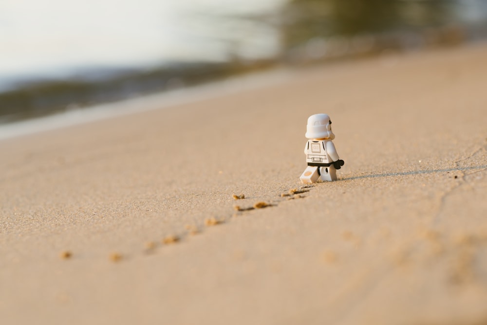 white lego toy on brown sand during daytime
