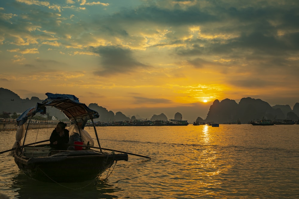 silhouette of people riding boat on sea during sunset