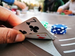Close-up of hands holding playing cards and chips on a digital casino table.