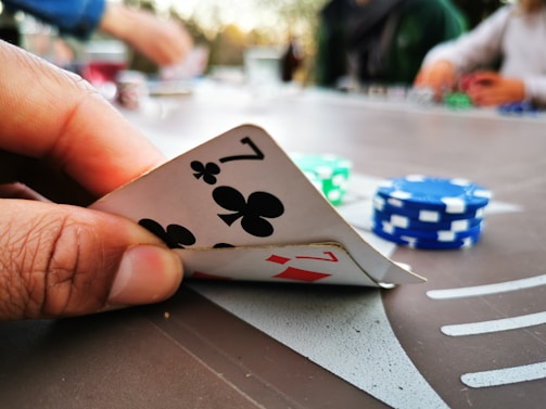 Close-up of a player’s hand holding winning rummy cards with chips stacked nearby.