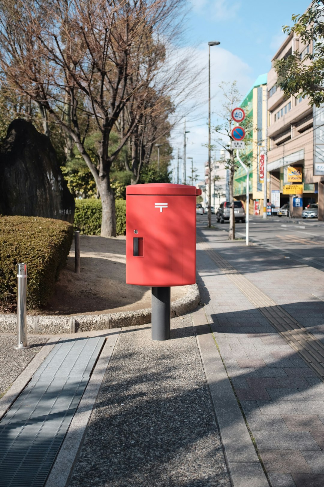 red and black trash bin on sidewalk during daytime