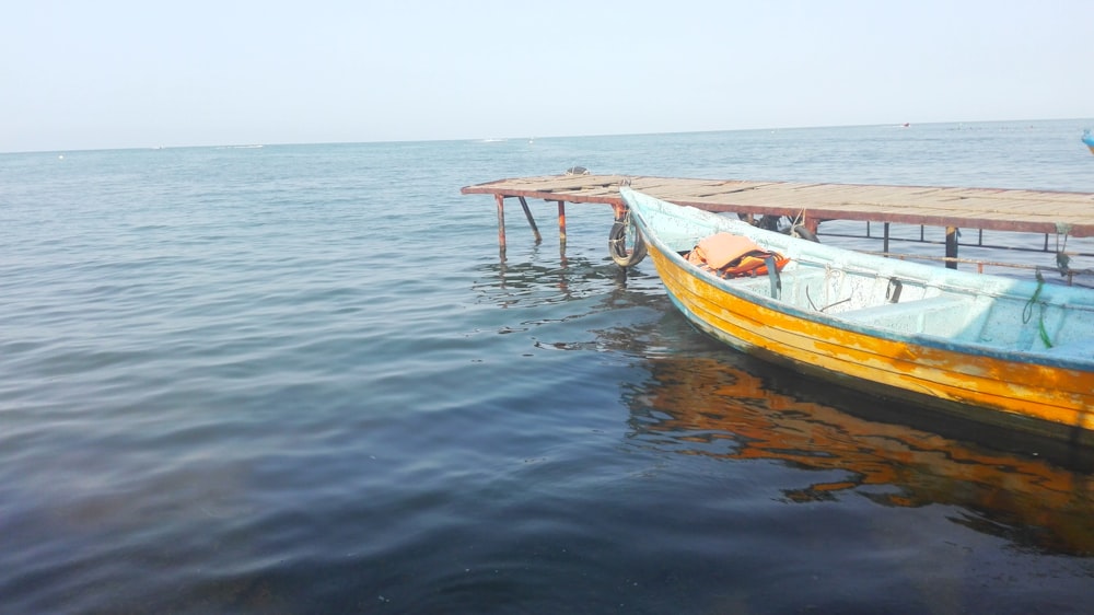 a yellow and blue boat sitting on top of a body of water