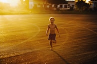 A candid shot of a child running through a sunlit field of wildflowers.