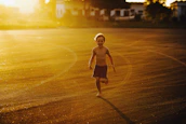 A cinematic capture of a child playing joyfully under golden sunlight, highlighting natural interactions.