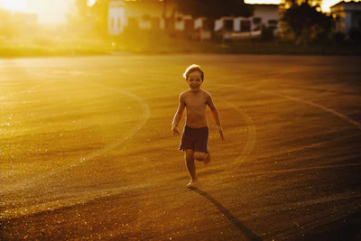 Children running barefoot through a sunlit field, carefree and joyful.