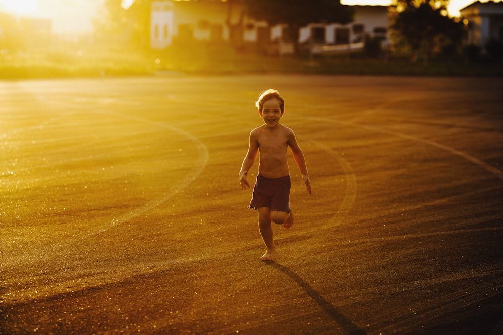 topless boy running on road during daytime