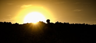 A silhouette of a person meditating at sunset on a hilltop.
