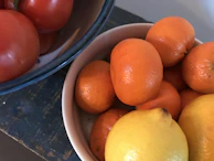 Close-up of a cheerful yellow ceramic bowl filled with fresh fruit on a rustic wooden table.