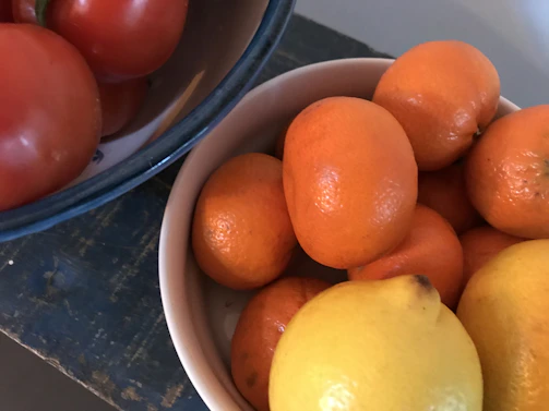 Close-up of a colorful ceramic bowl filled with fresh fruit on a rustic wooden table.
