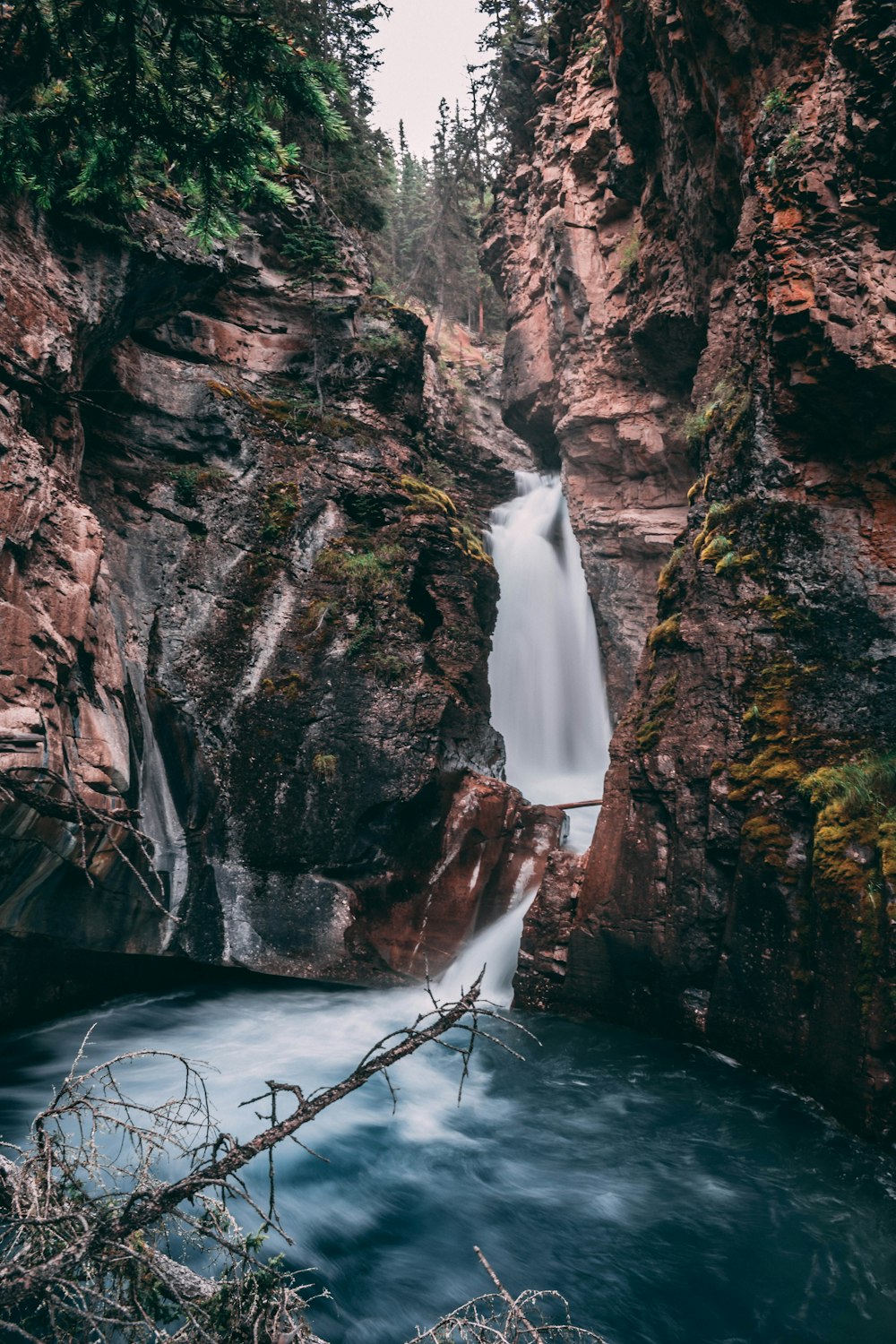 water falls between brown rocky mountain during daytime