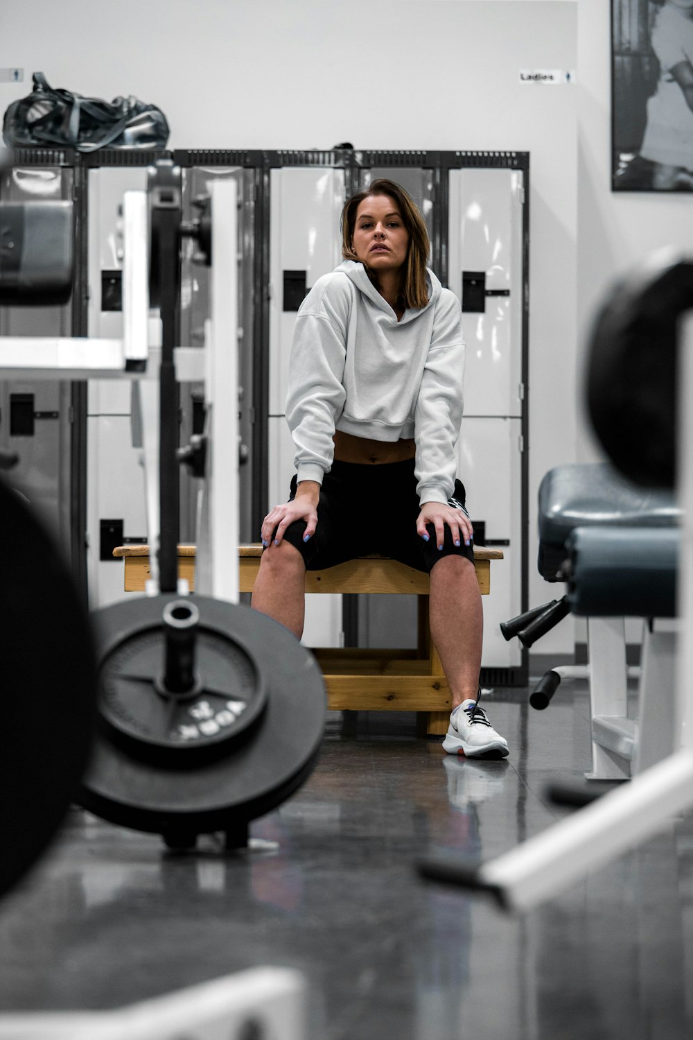 man in white long sleeve shirt and black shorts sitting on black and gray exercise bench