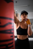 woman in black sports bra and black shorts holding orange bottle