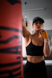 woman in black sports bra and black shorts holding orange bottle