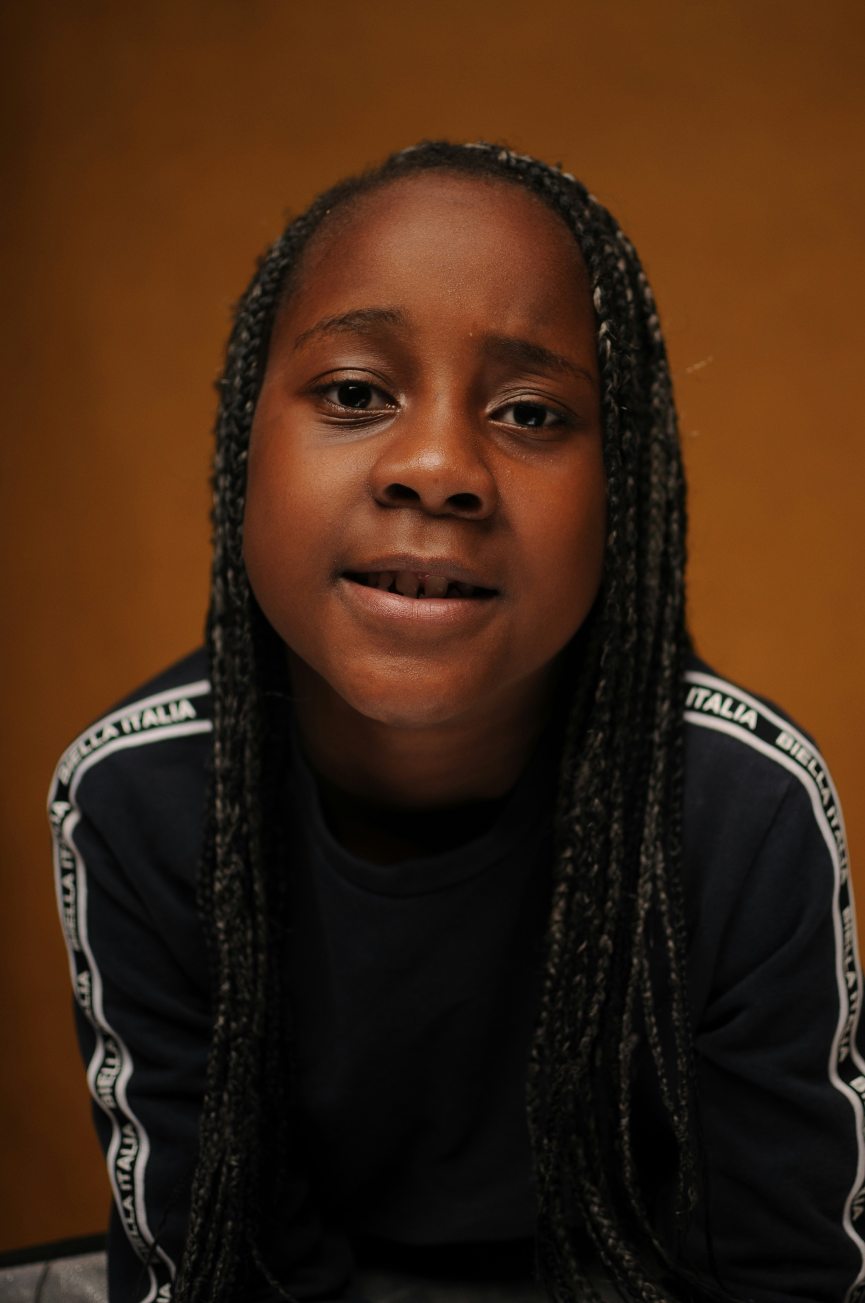 Child with neat cornrows, warm bright background, natural lighting, gentle atmosphere