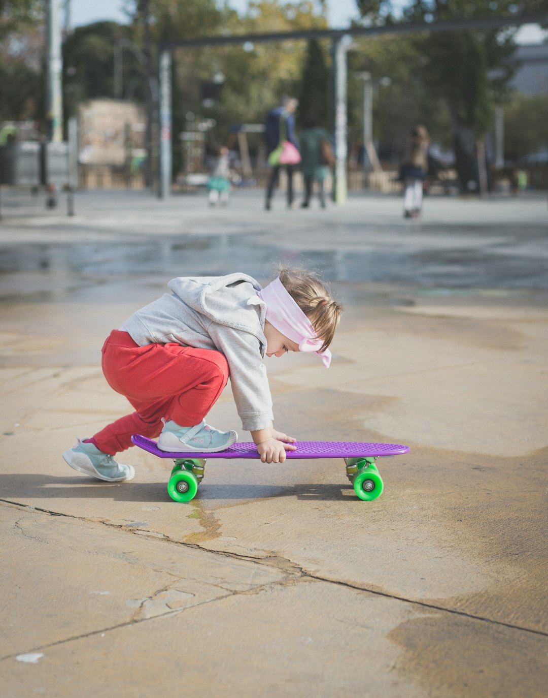 girl in white and red hoodie riding green kick scooter during daytime