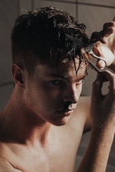 A man confidently cutting his own hair using a mirror.