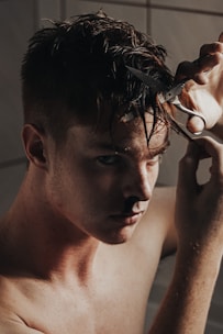 A man confidently cutting his own hair using a mirror.