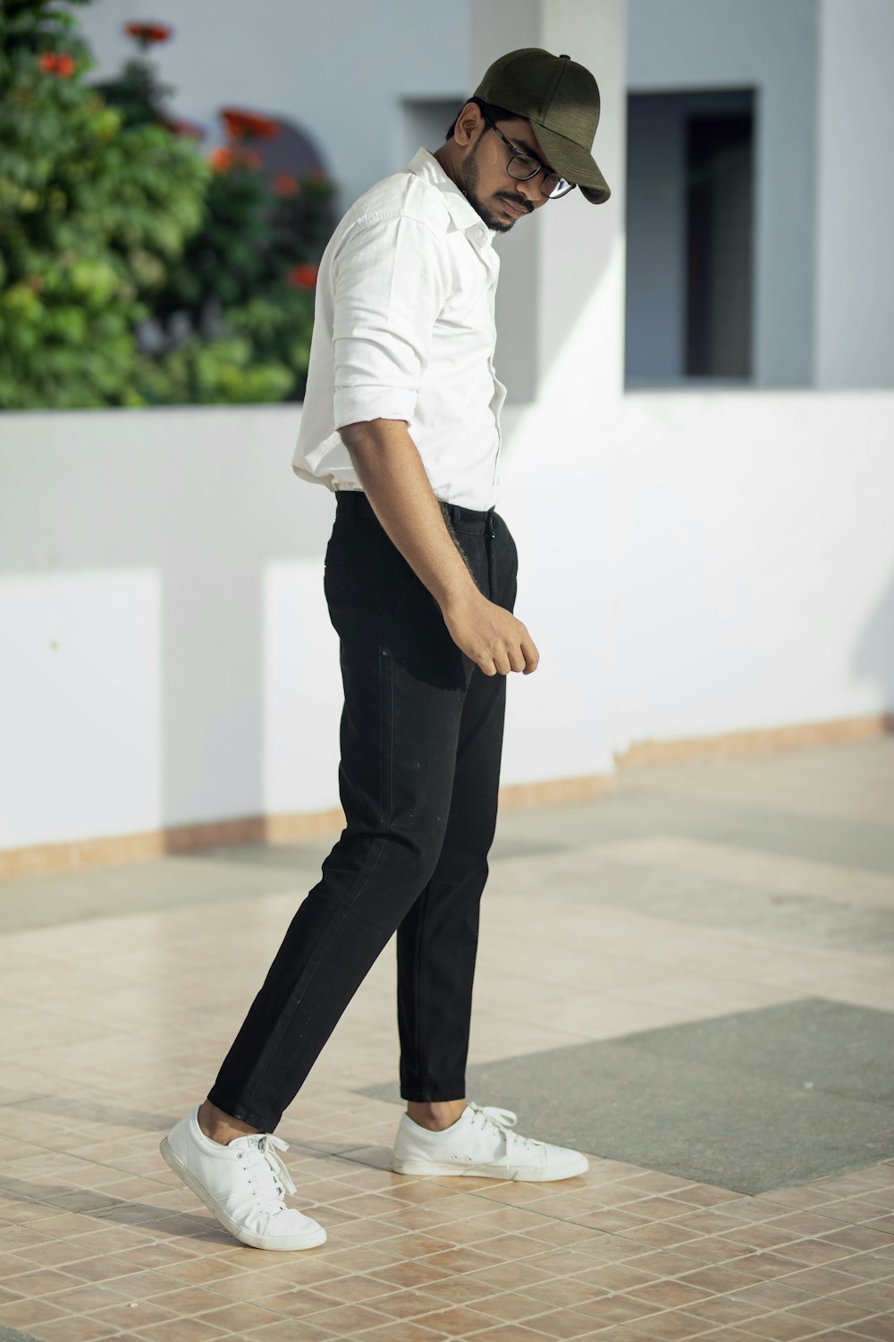 Hombre con camiseta blanca y pantalones negros de pie sobre el suelo blanco