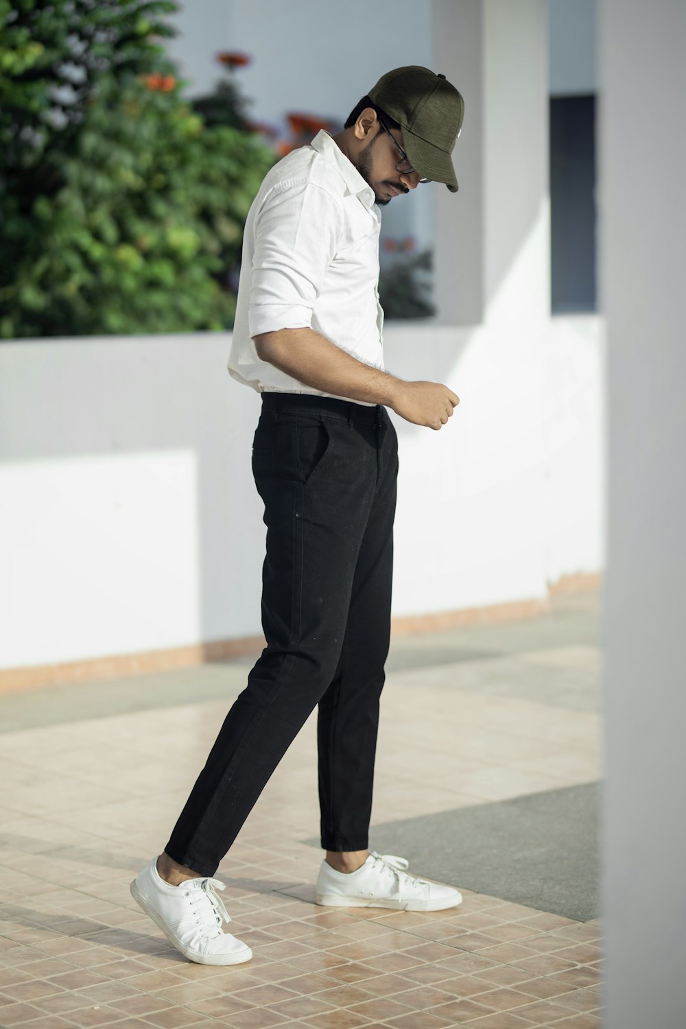 흰색 티셔츠와 검은 바지를 입은 남자가 흰색 바닥에 서 있다
