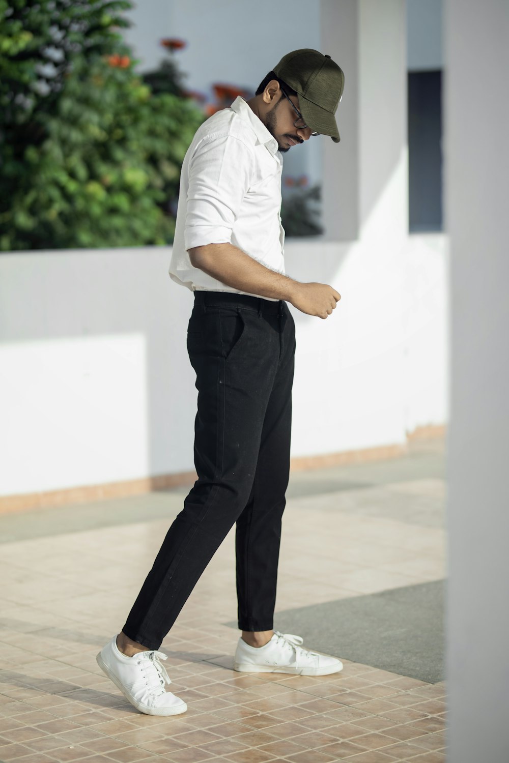 Hombre con camiseta blanca y pantalones negros de pie sobre el suelo blanco