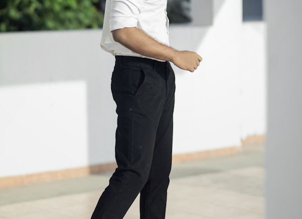 man in white t-shirt and black pants standing on white floor