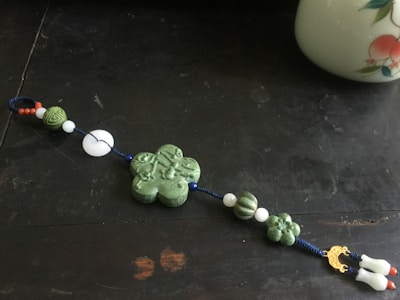 A collection of green and white charms displayed on a soft linen cloth.