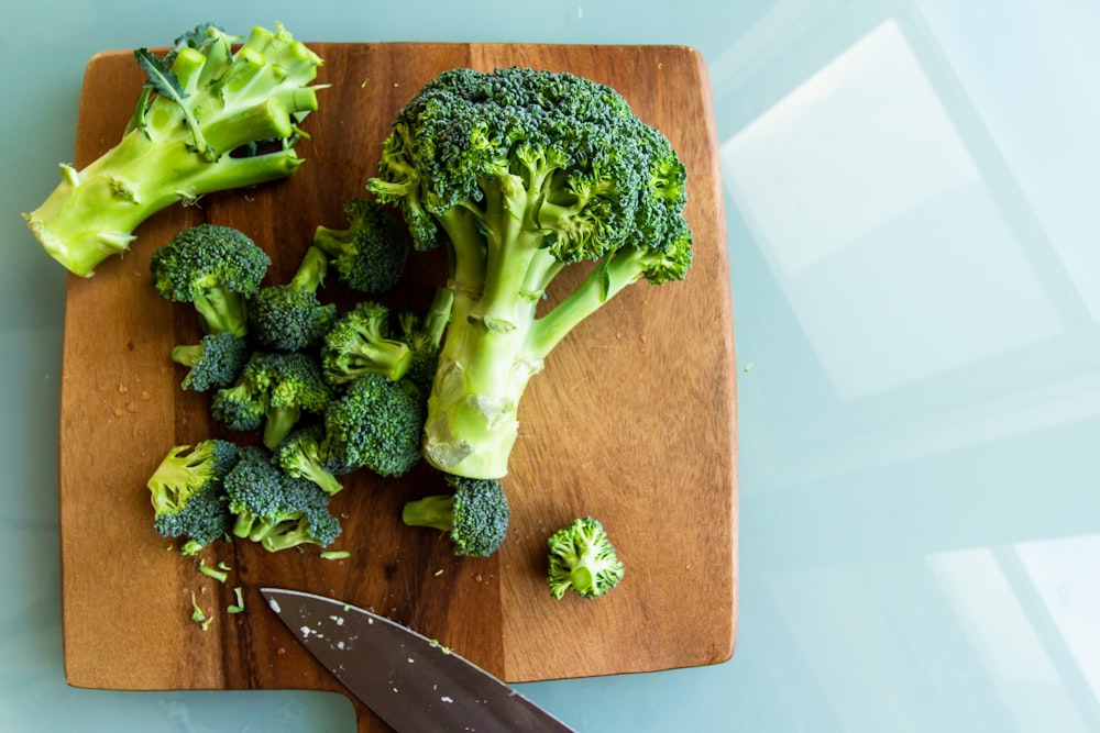 broccoli on brown wooden chopping board