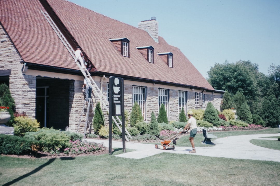 2 men sitting on bench near brown brick house during daytime