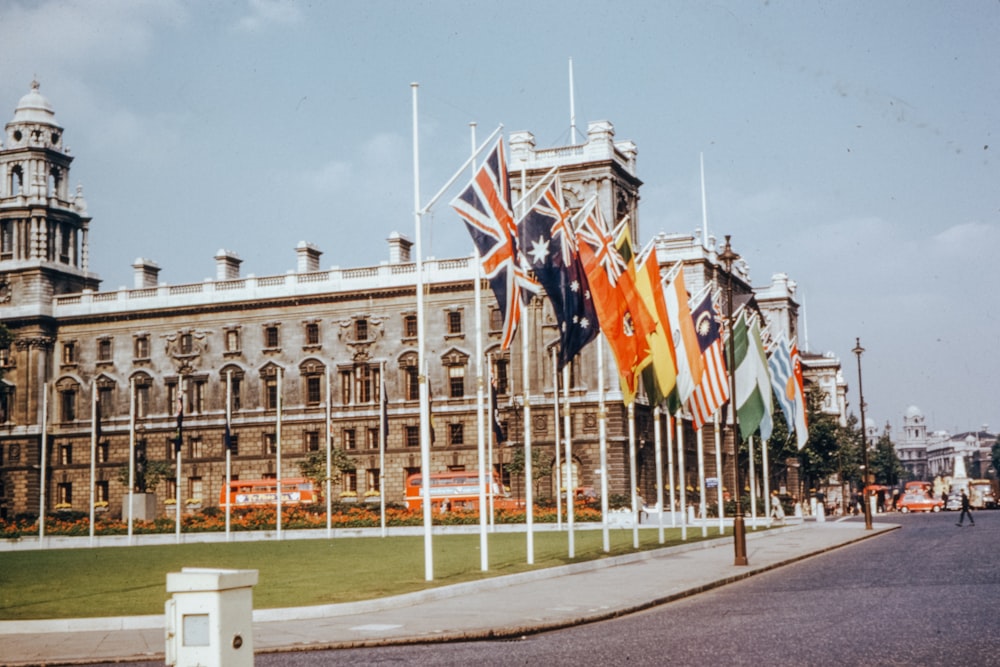 flags on poles on green grass field near white concrete building during daytime