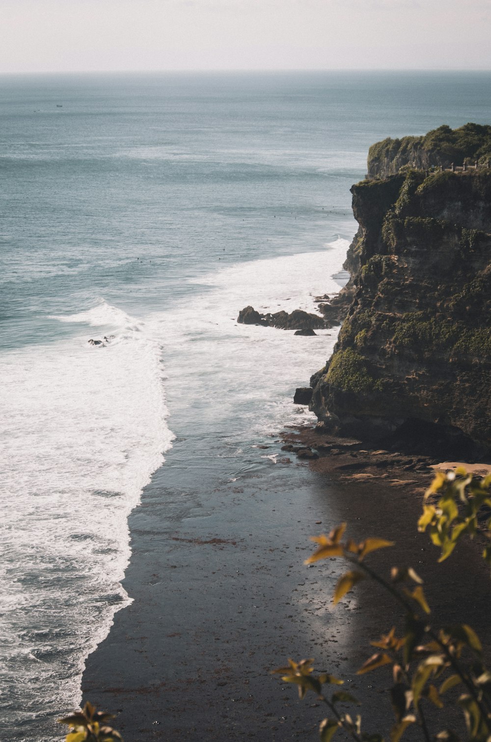 green and brown rock formation beside body of water during daytime