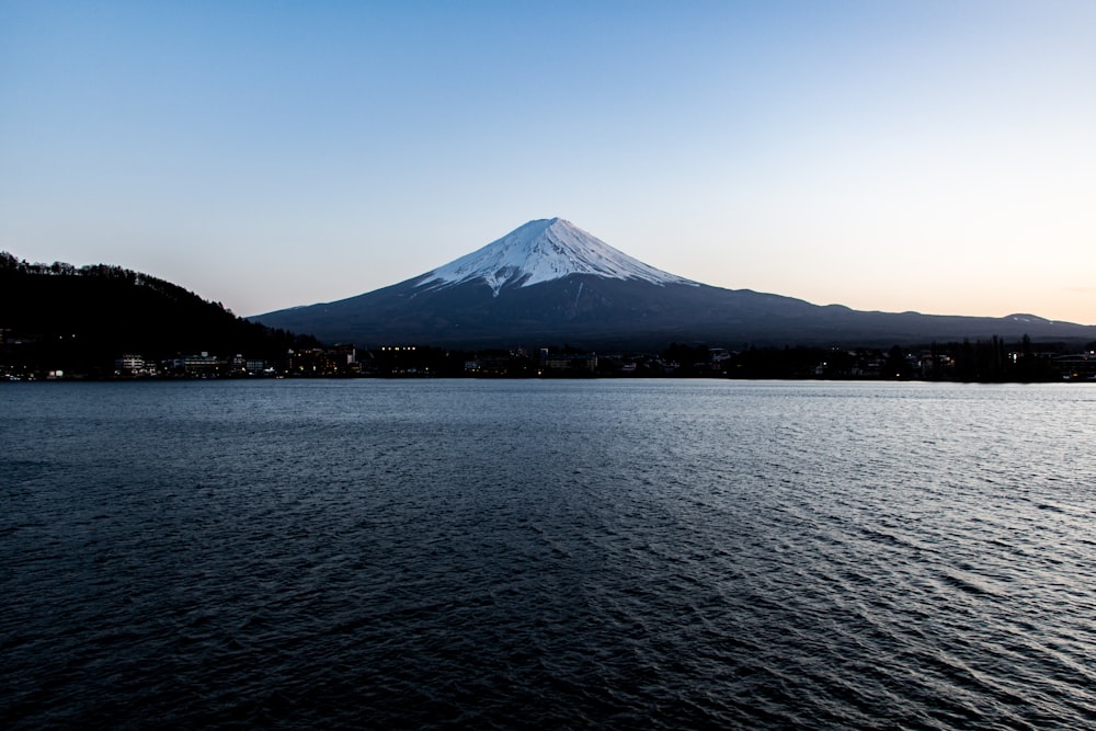 snow covered mountain near body of water during daytime