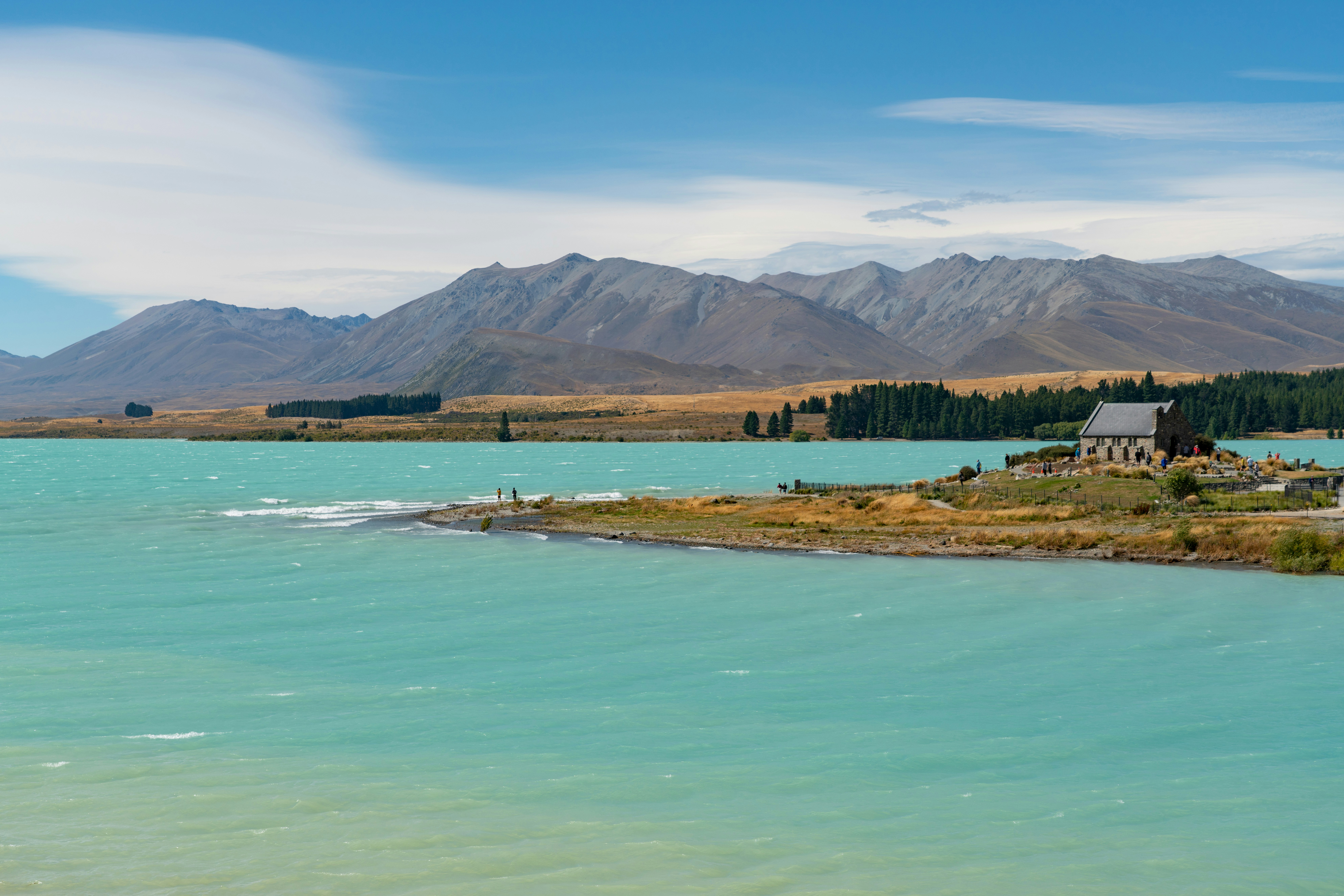 green and brown mountains beside body of water under blue sky during daytime