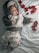 A baby dressed in a fuzzy, bear-themed hoodie and cloud-printed pants lies on a light blue, textured blanket. Red rose petals are scattered around them, adding a touch of color to the serene and cozy setting.
