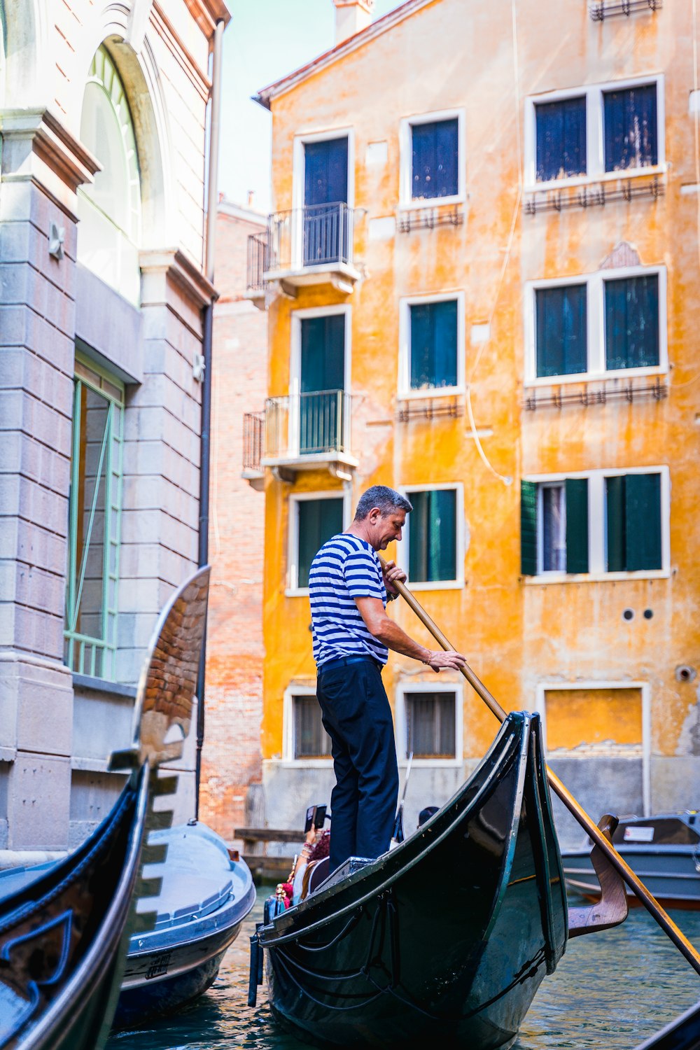 man in black and white striped long sleeve shirt riding on black boat during daytime