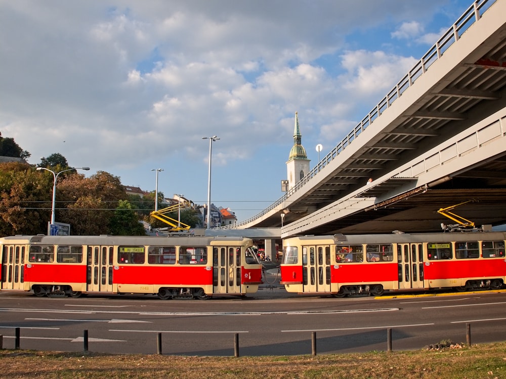 red and white train on rail road under cloudy sky during daytime