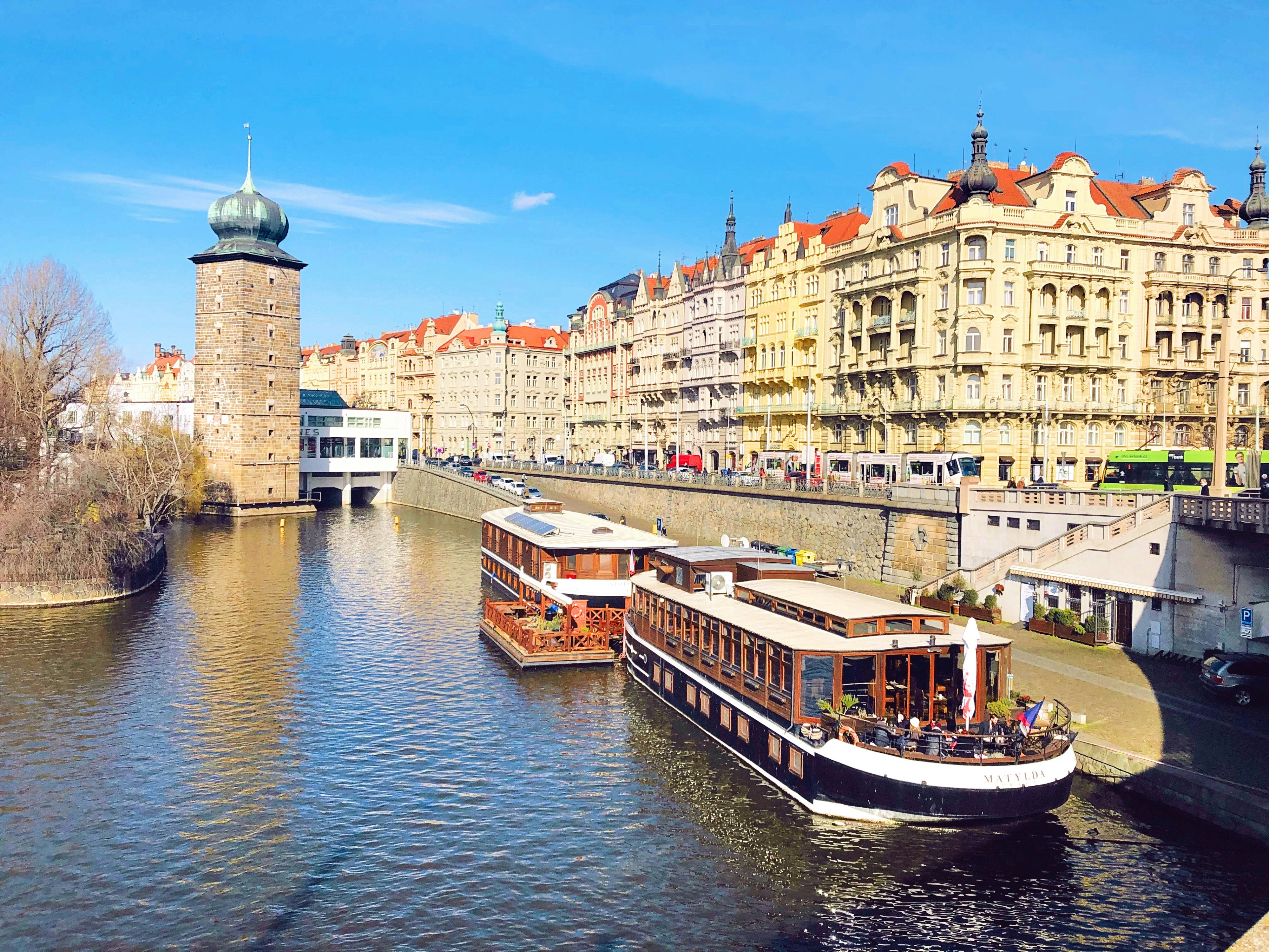 white and brown boat on river near brown concrete building during daytime