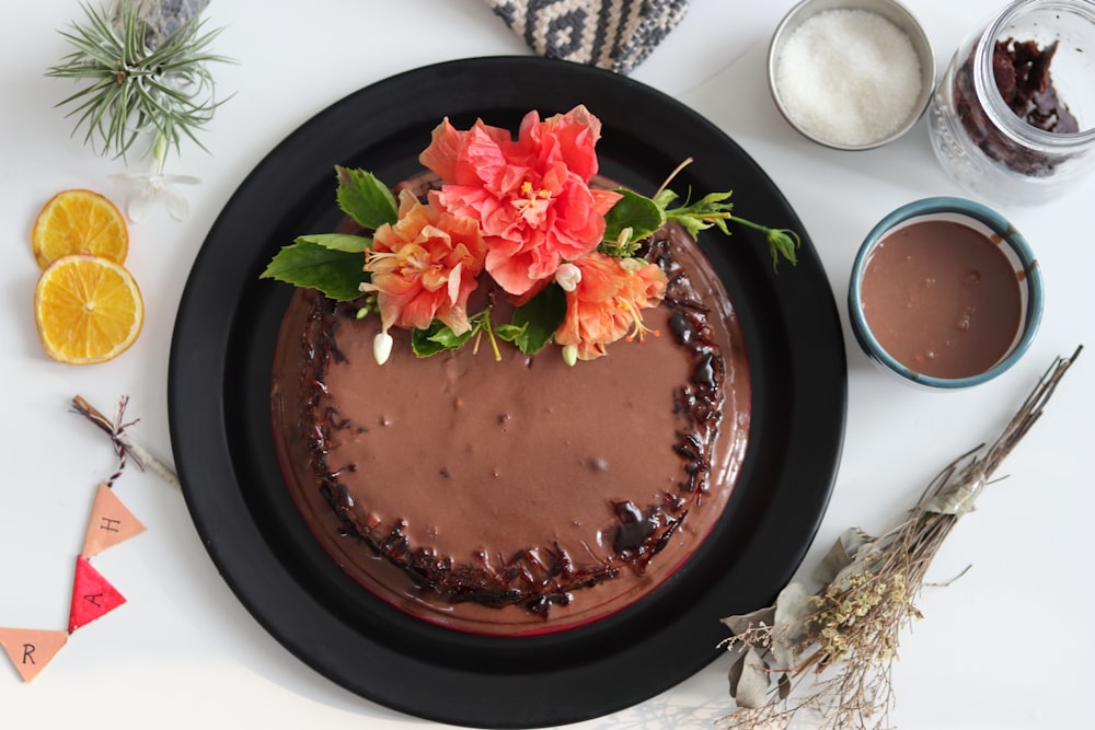 chocolate cake with pink flower on black ceramic plate