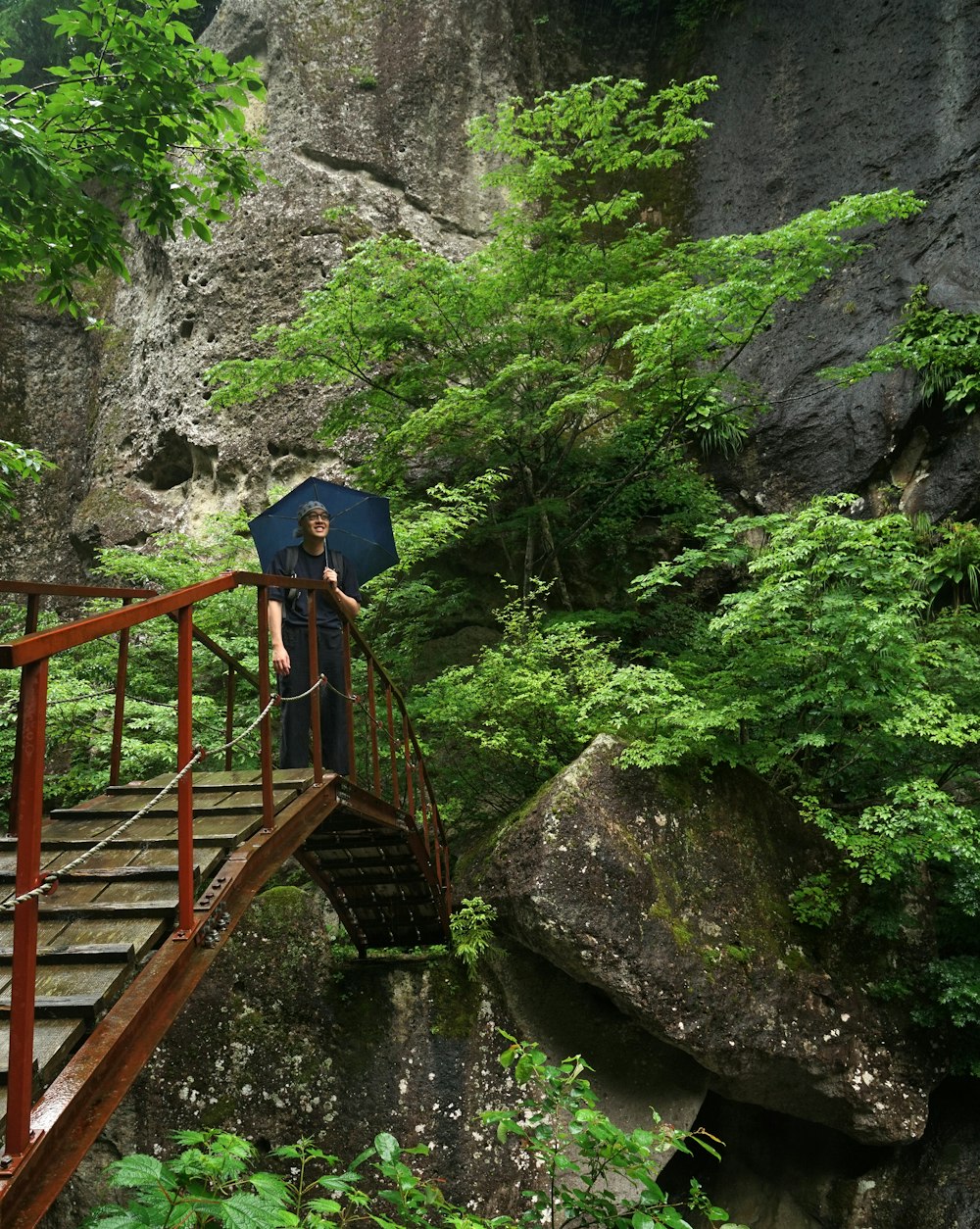 a man standing on a bridge holding an umbrella