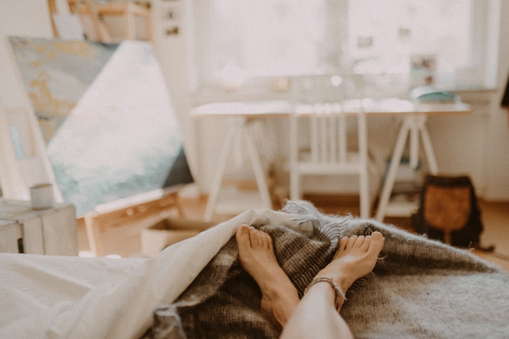 person lying on bed covered with blanket